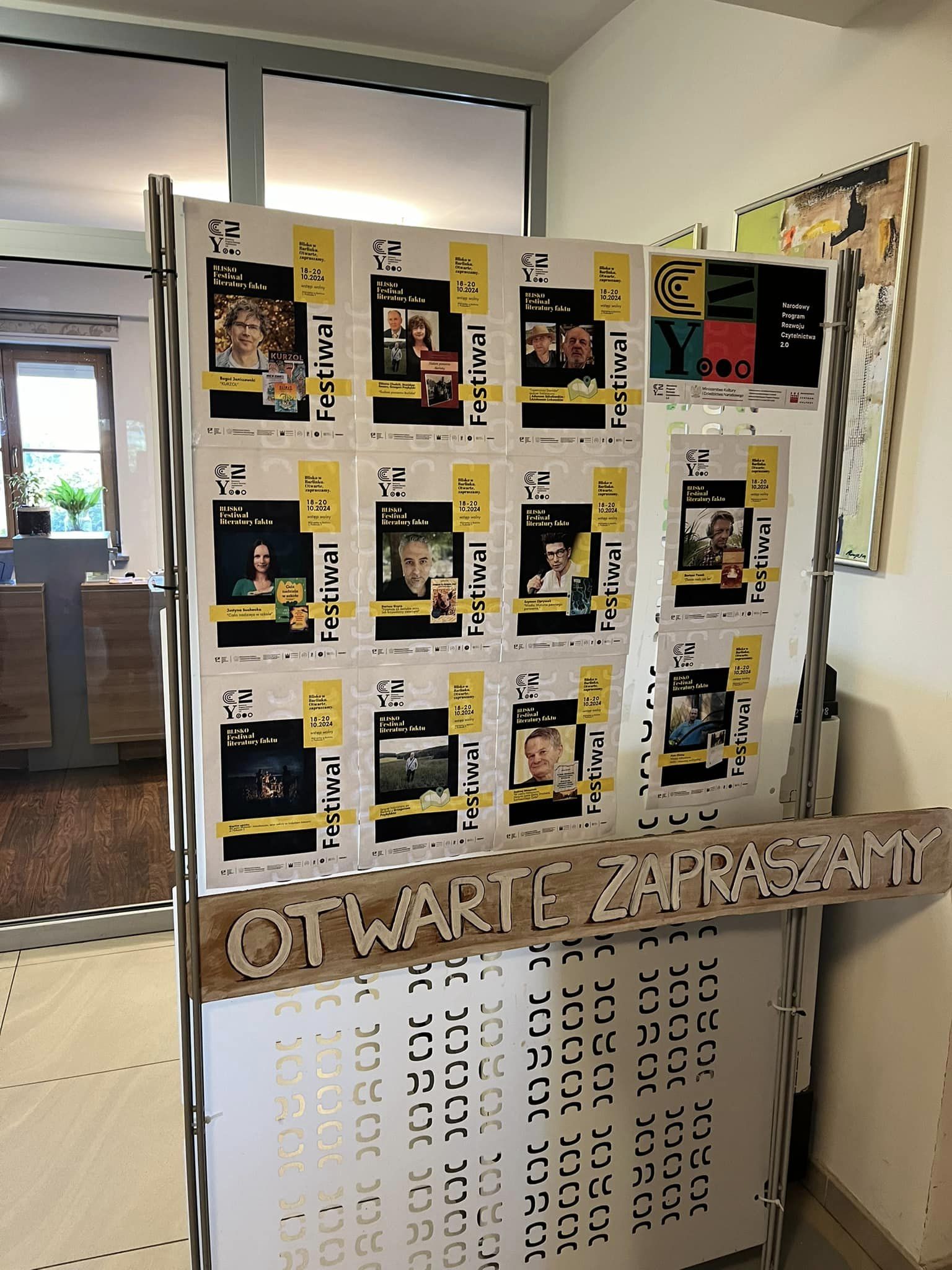 w budynku Barlineckiego Ośrodka Kultury stoi przenośna ścianka z przyklejonymi plakatami z wizerunkami gości festiwalowych. Pod zdjęciami przyczepiony jest napis “Otwarte, zapraszamy!”