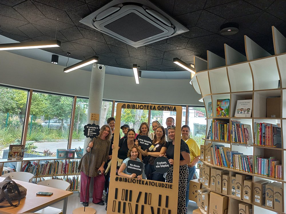 na zdjęciu widać grupę 11 osób pozujących do zdjęcia w bibliotece dziecięcej w Gdyni