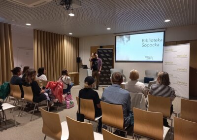 na zdjęciu widać grupę 9 osób słuchających prelekcji w bibliotece w Sopocie