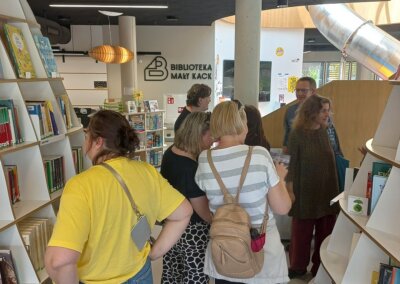 na zdjęciu widać kilkuosobową grupę osób stojących i oglądających książki w nowoczesnej bibliotece w Gdyni