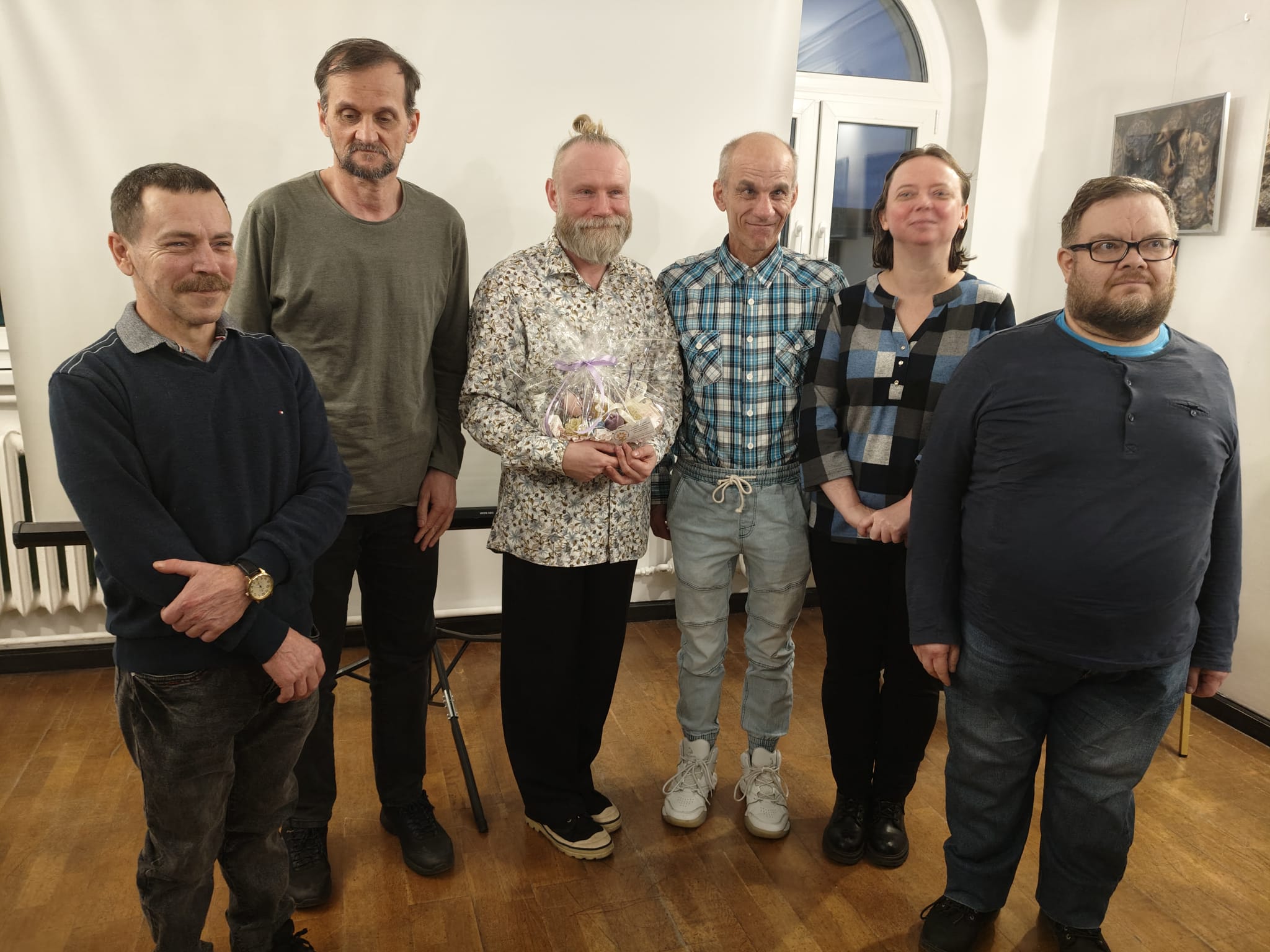 Pamiątkowe zdjęcie po zakończeniu prelekcji w Muzeum Regionalne w Barlinku. W centrum stoi prelegent Grzegorz Przybylski trzymający upominek, obok niego stoją uczestnicy wydarzenia.